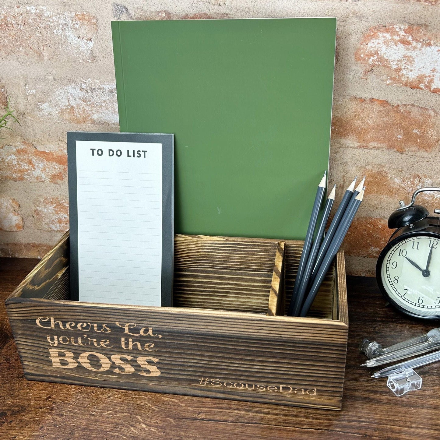 a desk with a clock, notepad and pen holder