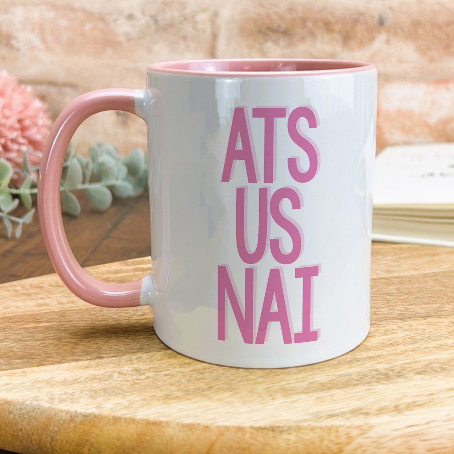 a pink and white coffee mug sitting on top of a wooden table