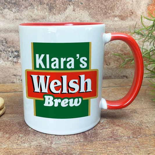 A white mug with a red handle, featuring a green and red logo that says "Klara's Welsh Brew".
