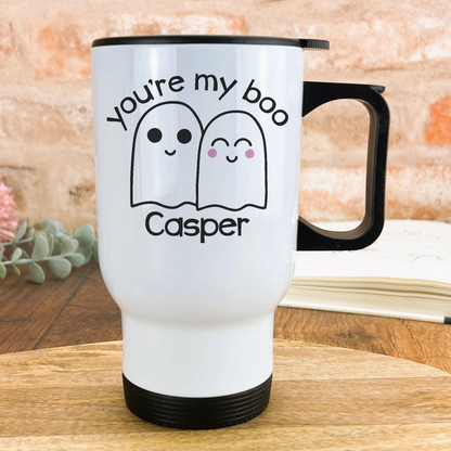 A white travel mug with a black handle, featuring a design of two ghostly figures and the text "You're my boo Casper" printed on it.