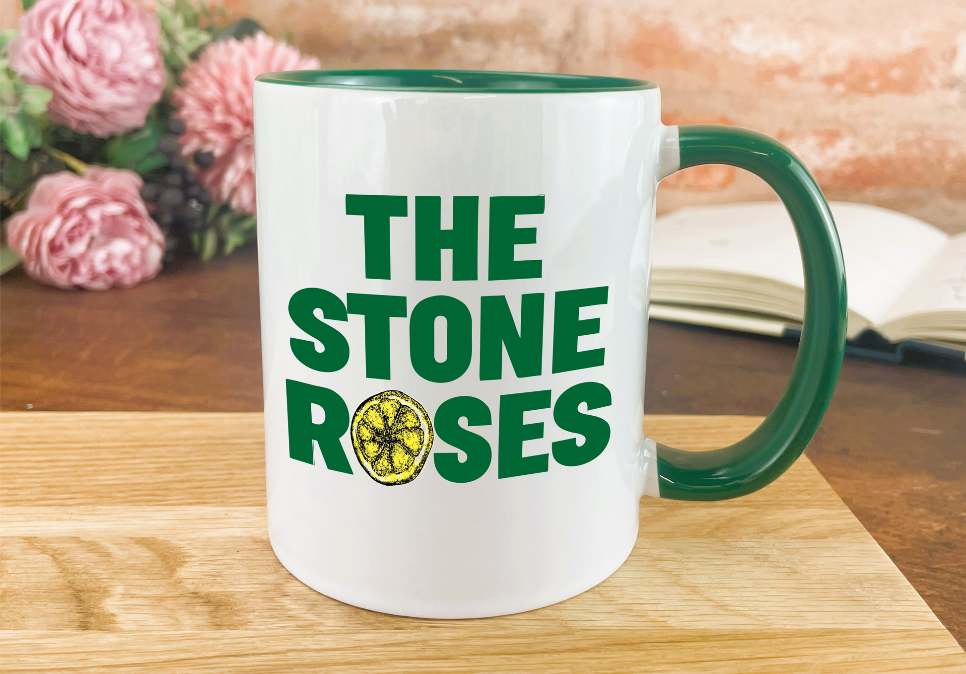 a green and white coffee mug with the stone roses on it