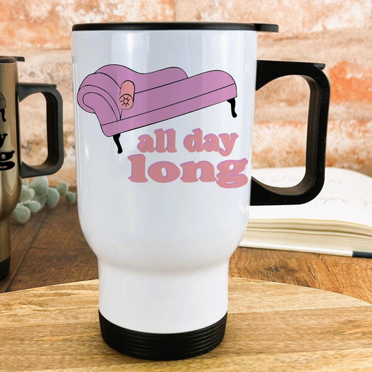 A white travel mug with a black handle and a pink couch graphic printed on it, sitting on a wooden surface.