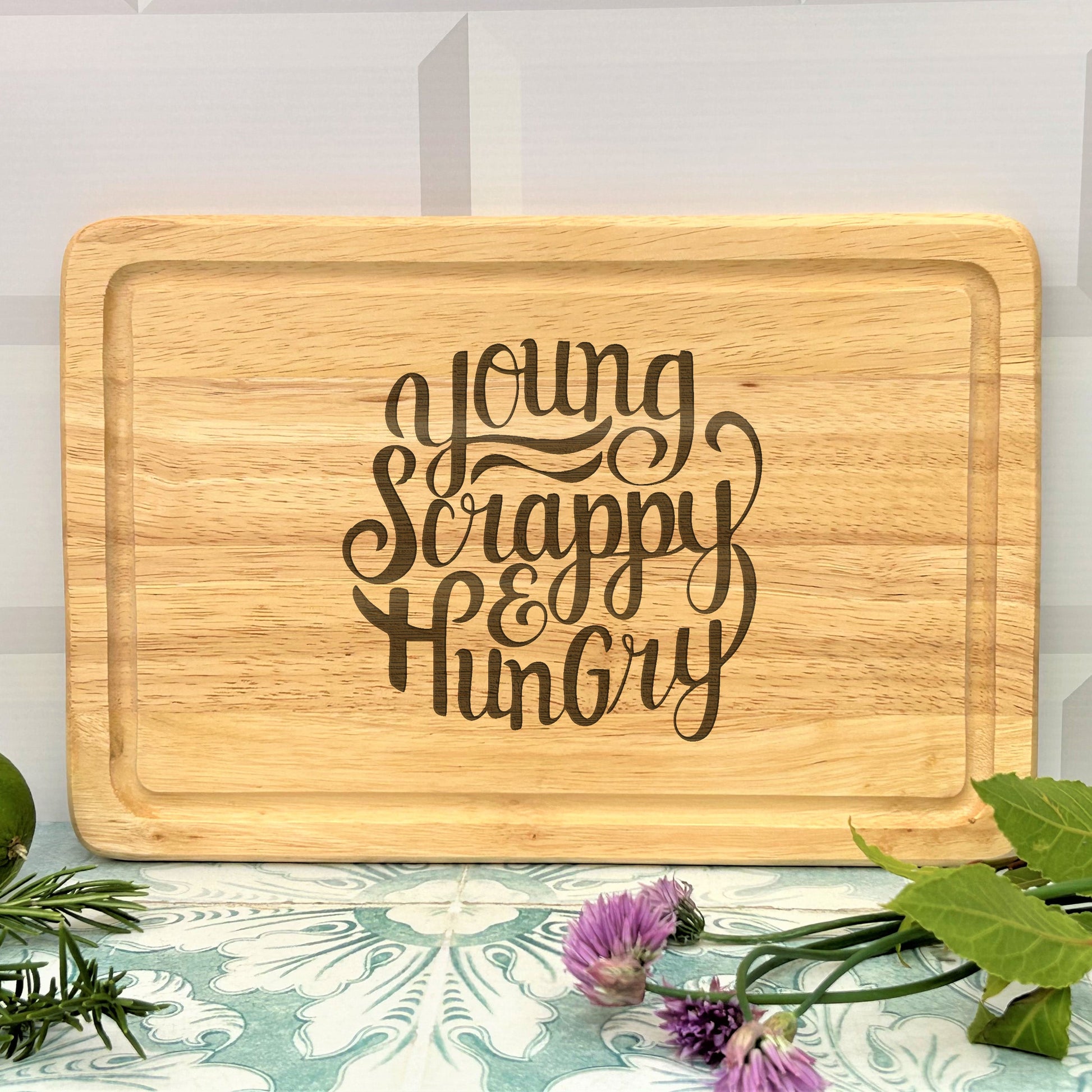 a wooden cutting board with the words young, happy, hungry on it