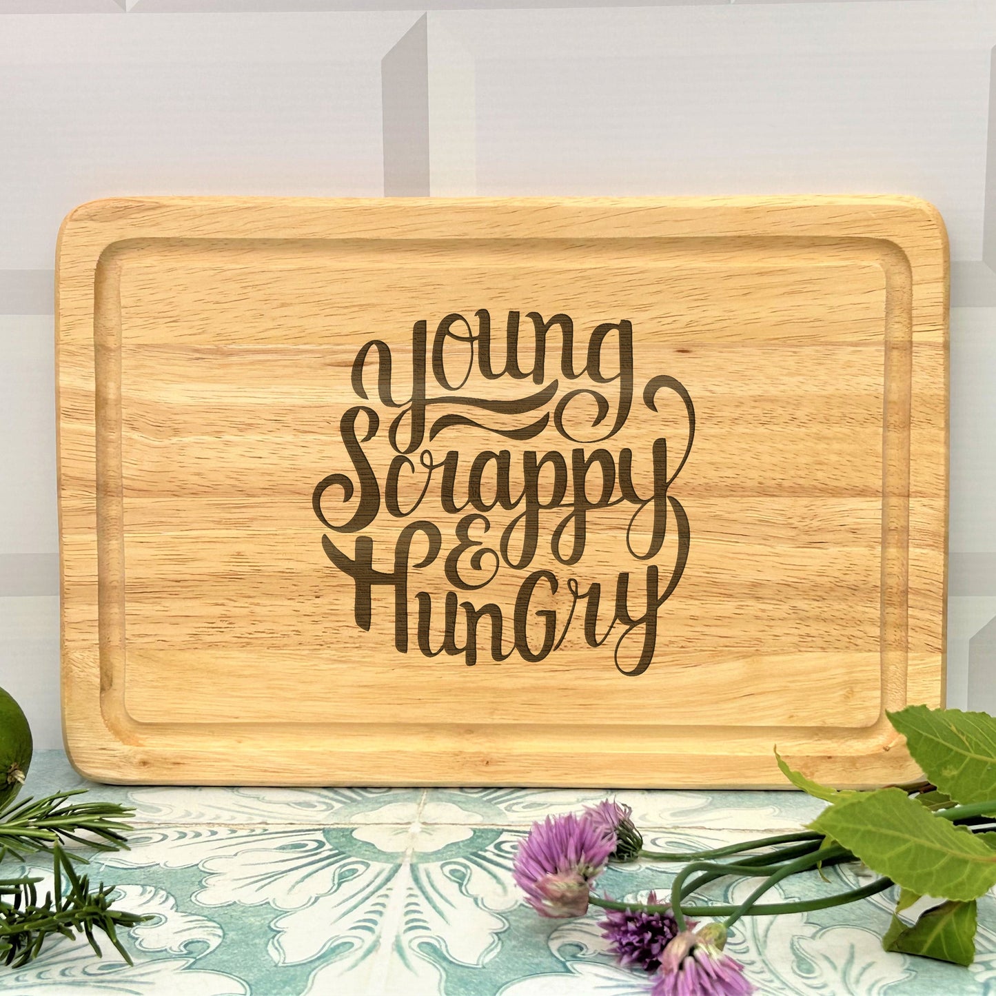 a wooden cutting board with the words young, happy, hungry on it