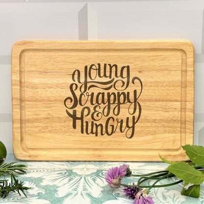 a wooden cutting board with the words young, happy, hungry on it