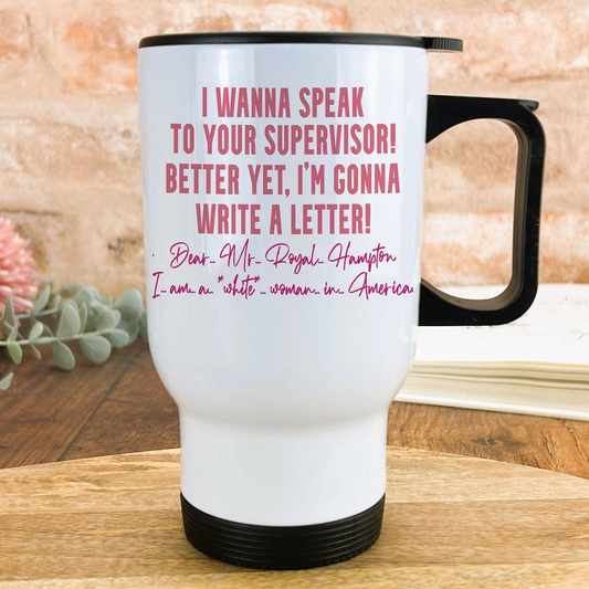 A white travel mug with text printed on it, placed on a wooden surface.