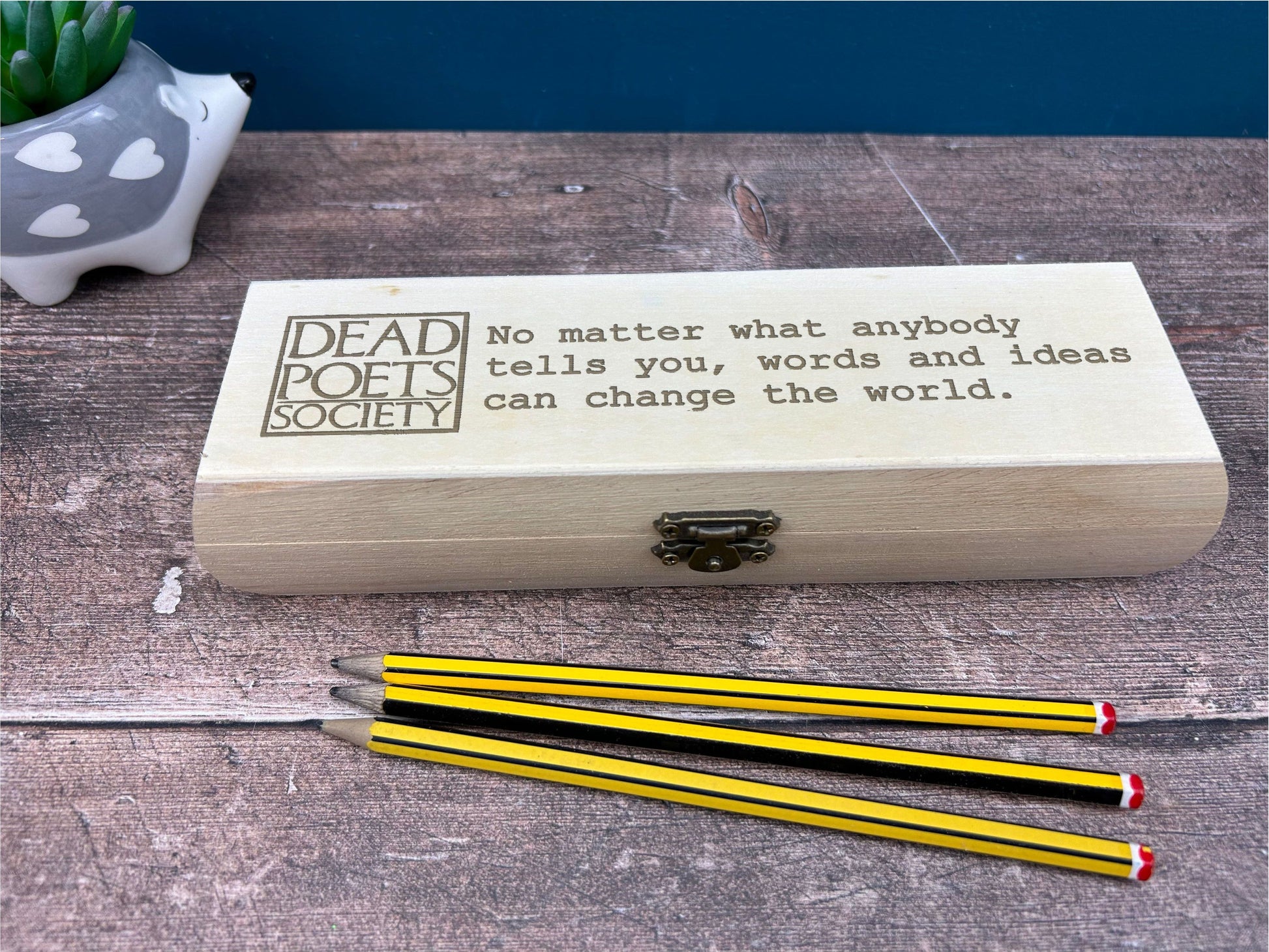 two pencils and a wooden box with a quote on it