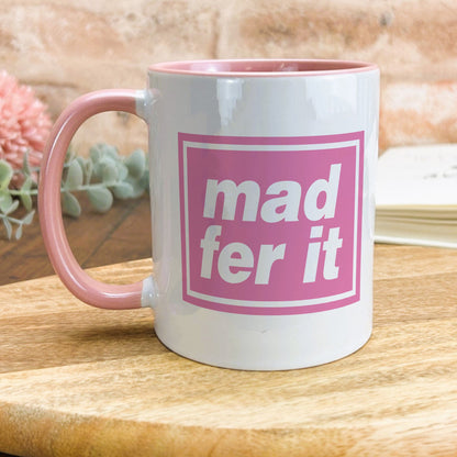 a pink and white mug sitting on top of a wooden table
