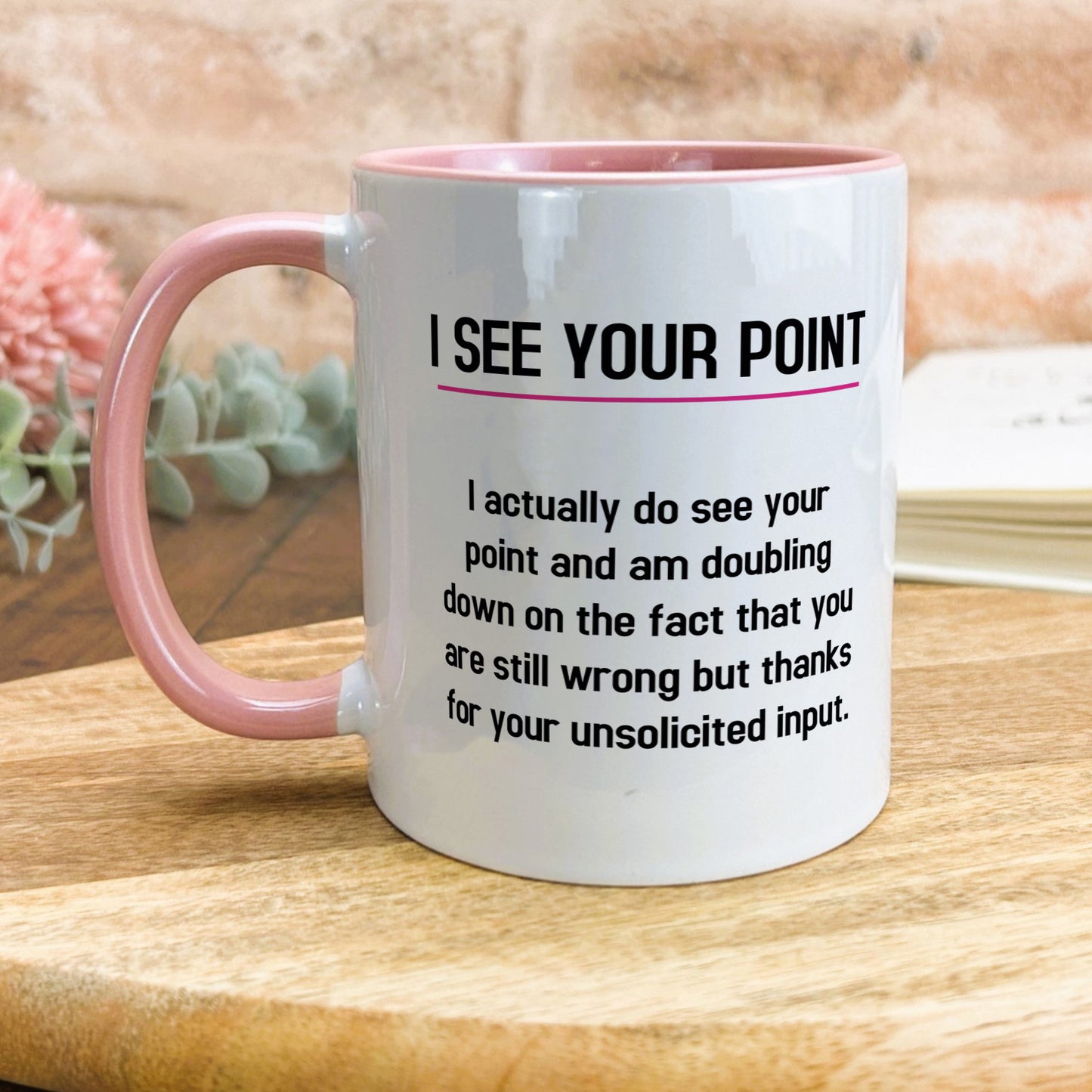 a pink and white coffee mug sitting on top of a wooden table