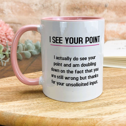 a pink and white coffee mug sitting on top of a wooden table