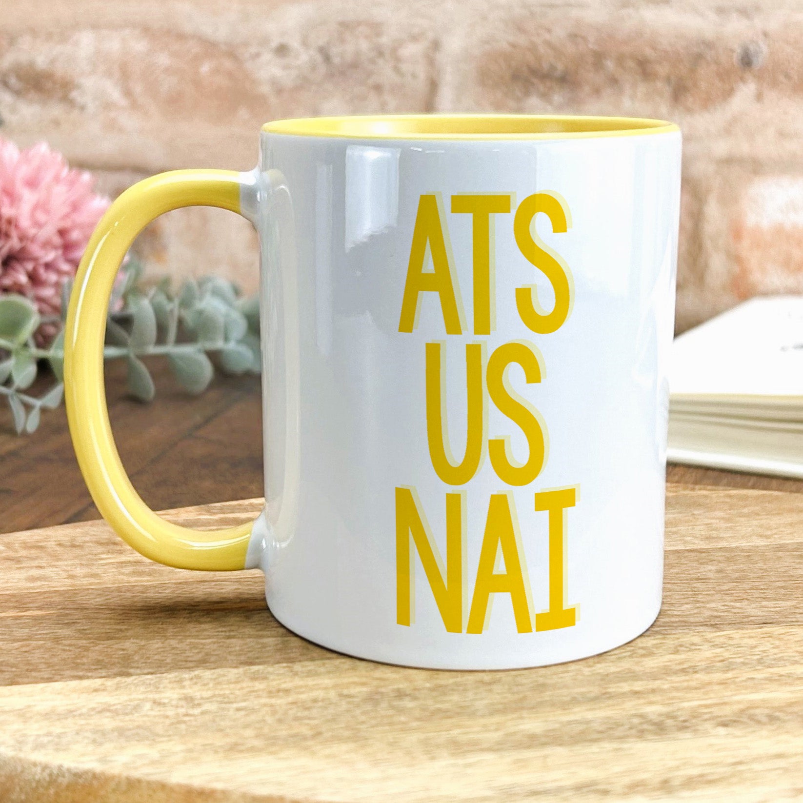 a yellow and white coffee mug sitting on top of a wooden table