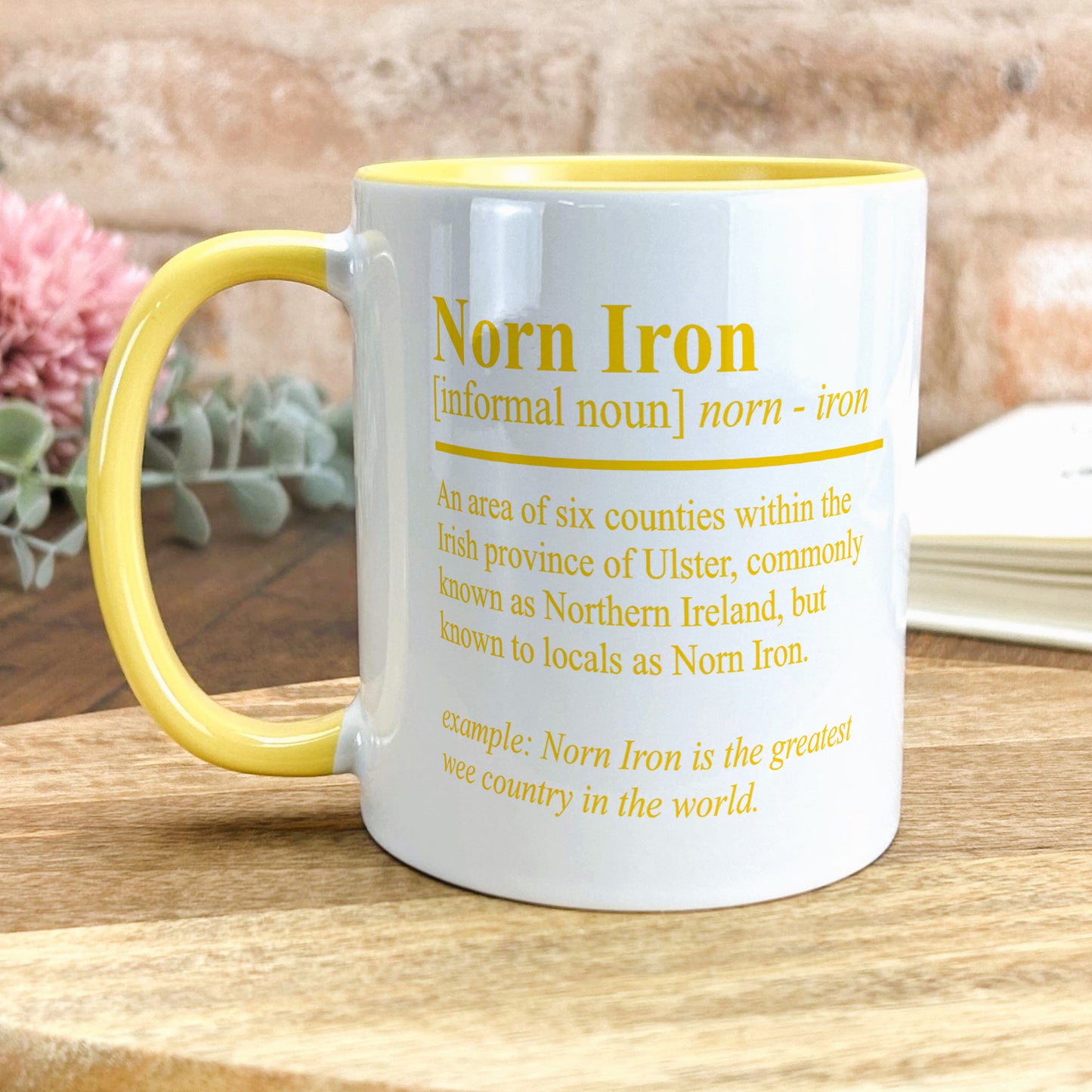 a yellow and white coffee mug sitting on top of a wooden table