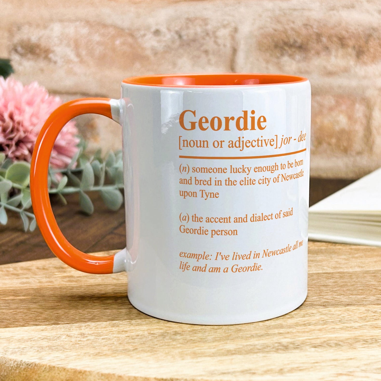 an orange and white coffee mug sitting on top of a wooden table
