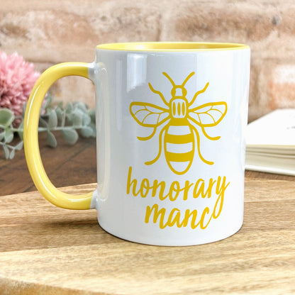 a yellow and white coffee mug with a bee on it