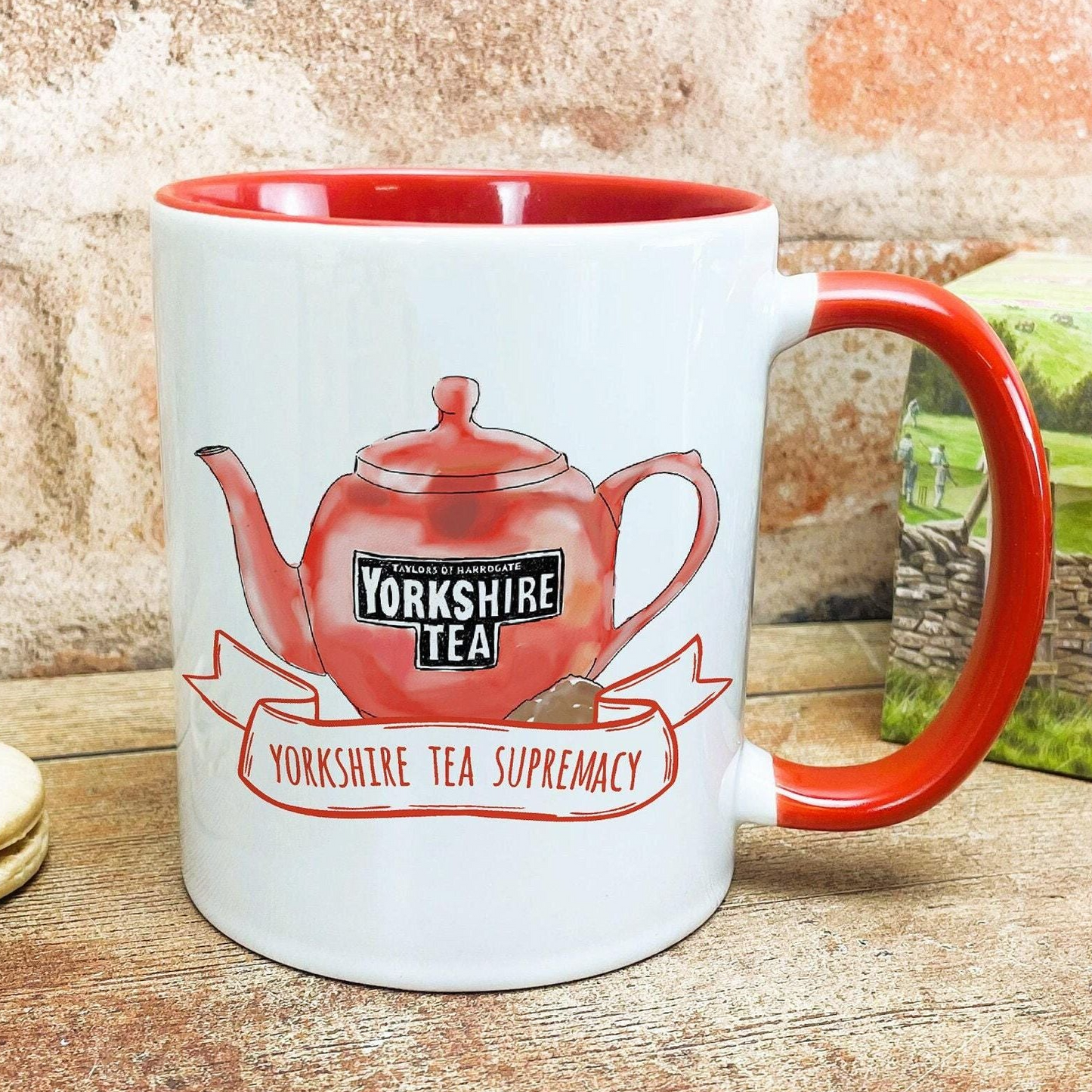 A white mug with a red rim, featuring an illustration of a red teapot and the text "Yorkshire Tea" and "Yorkshire Tea Supremacy".