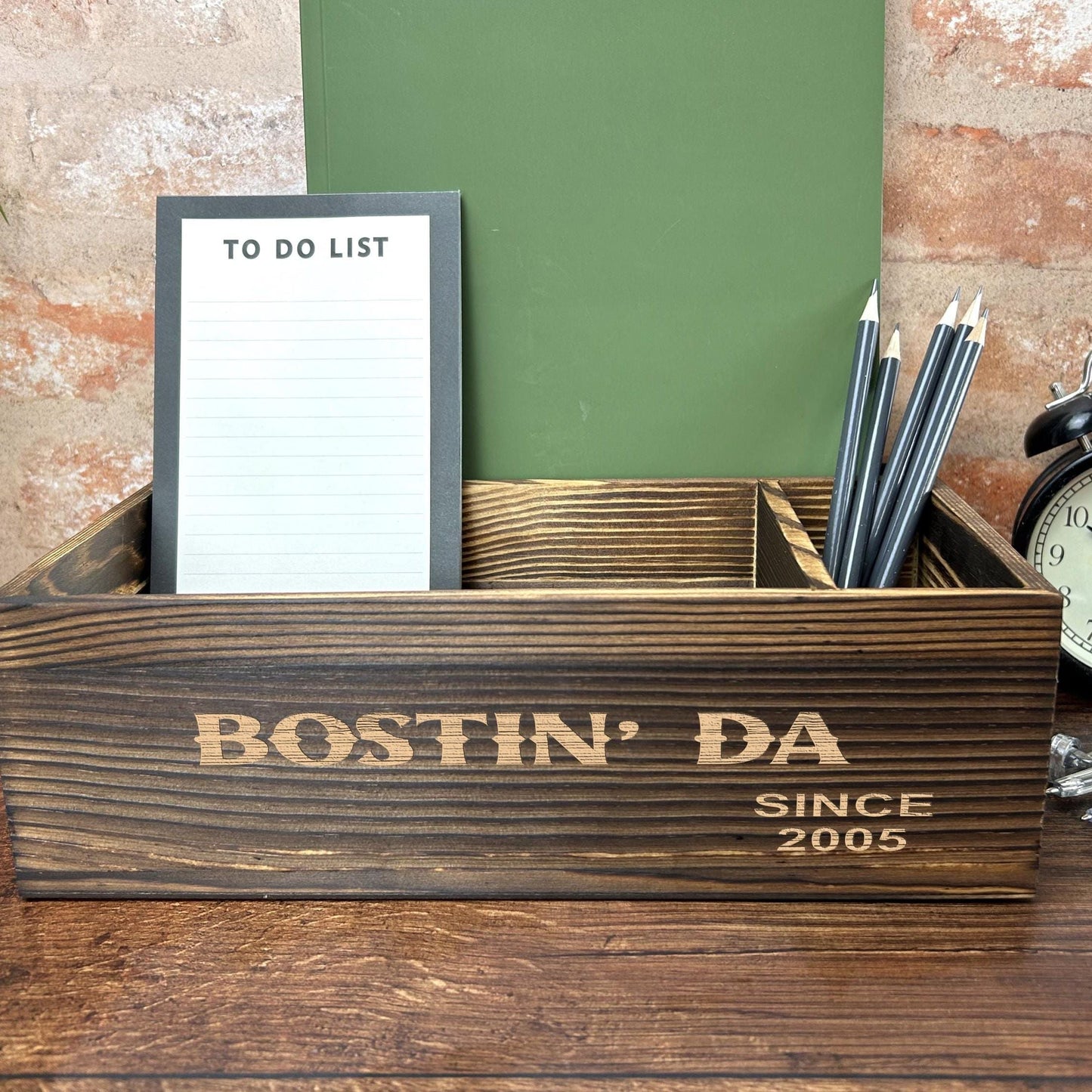 a desk with a clock, notepad and pen holder