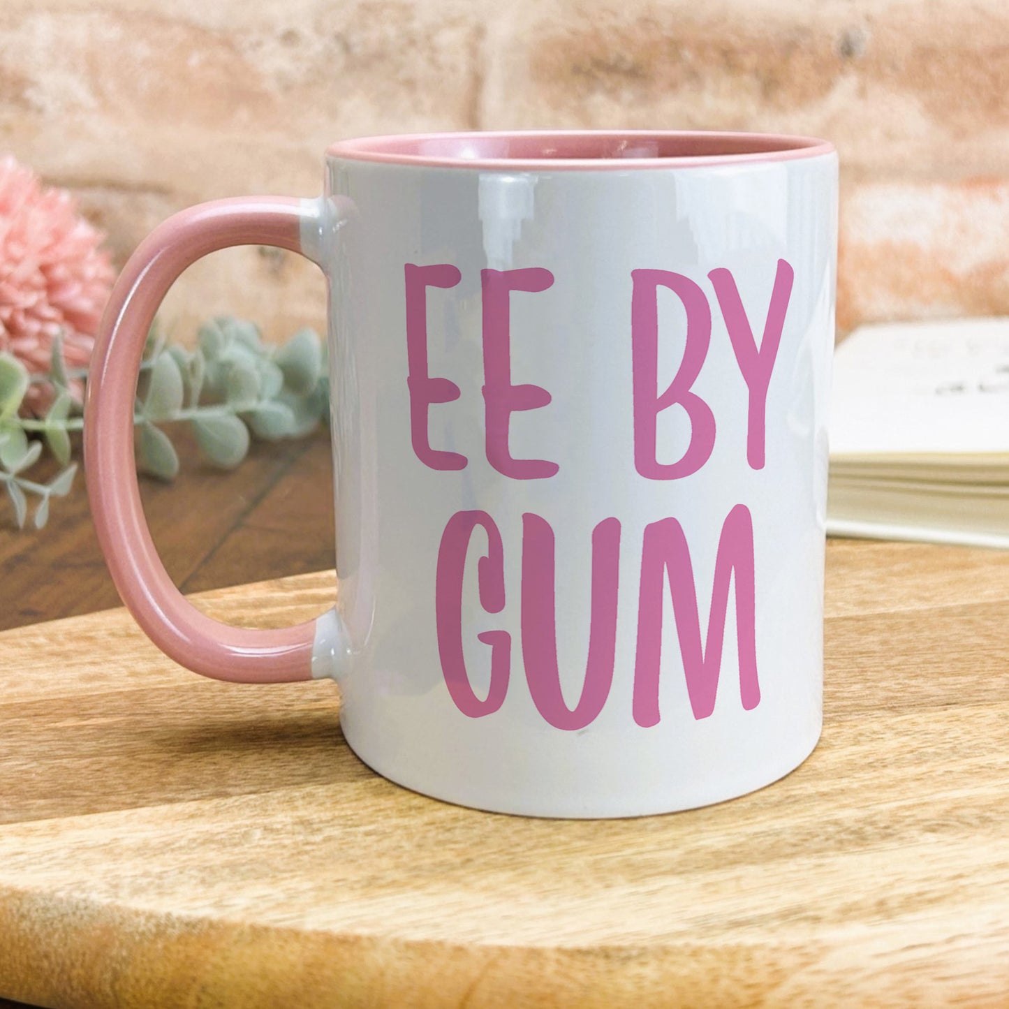 a pink and white coffee mug sitting on top of a wooden table
