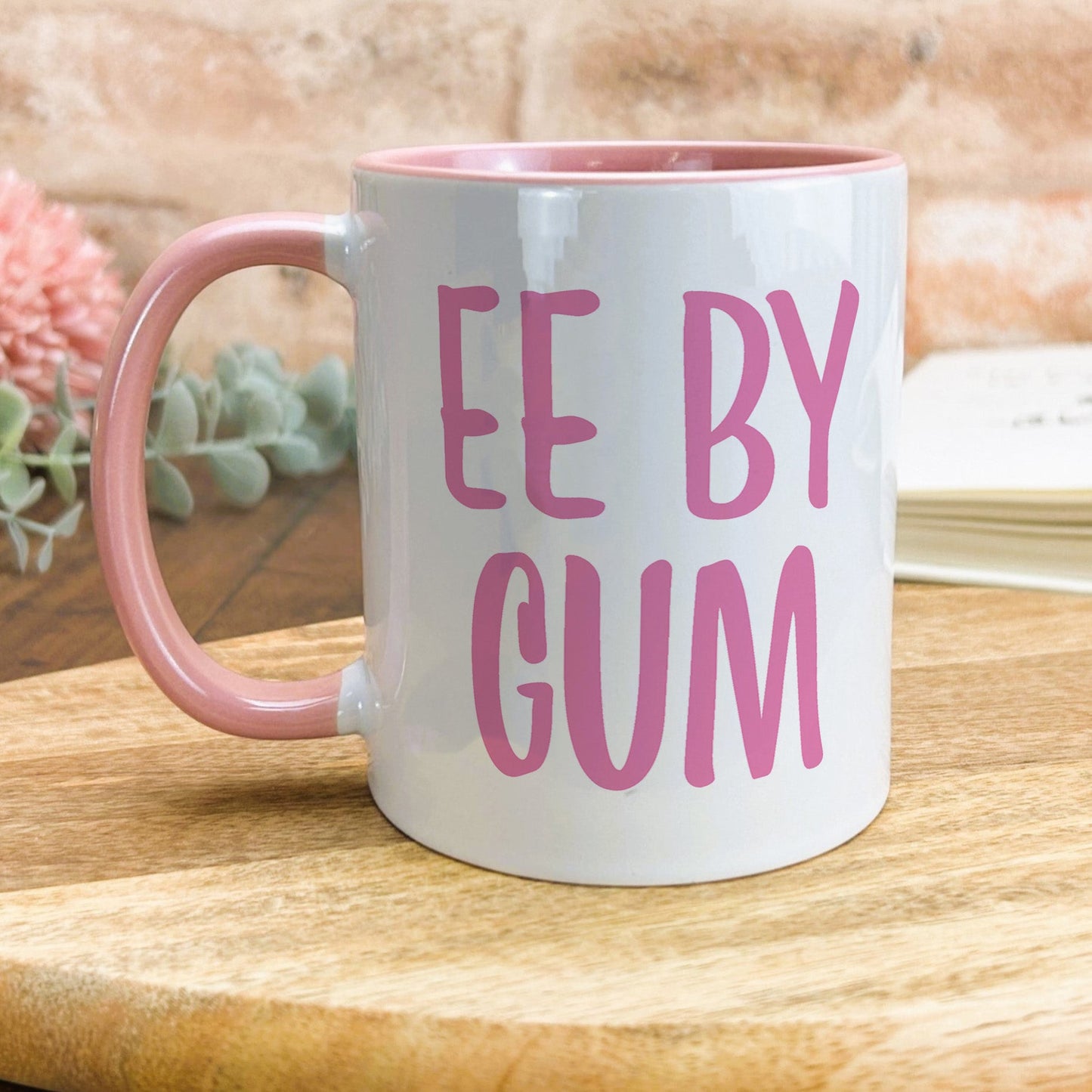 a pink and white coffee mug sitting on top of a wooden table