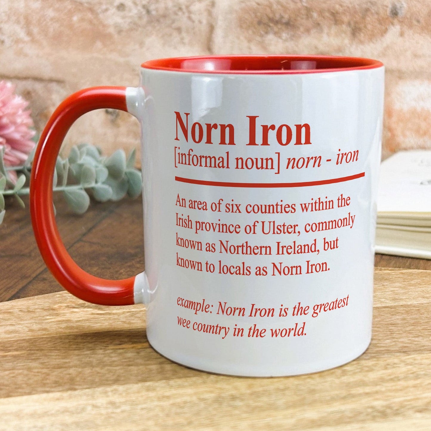 a red and white coffee mug sitting on top of a wooden table