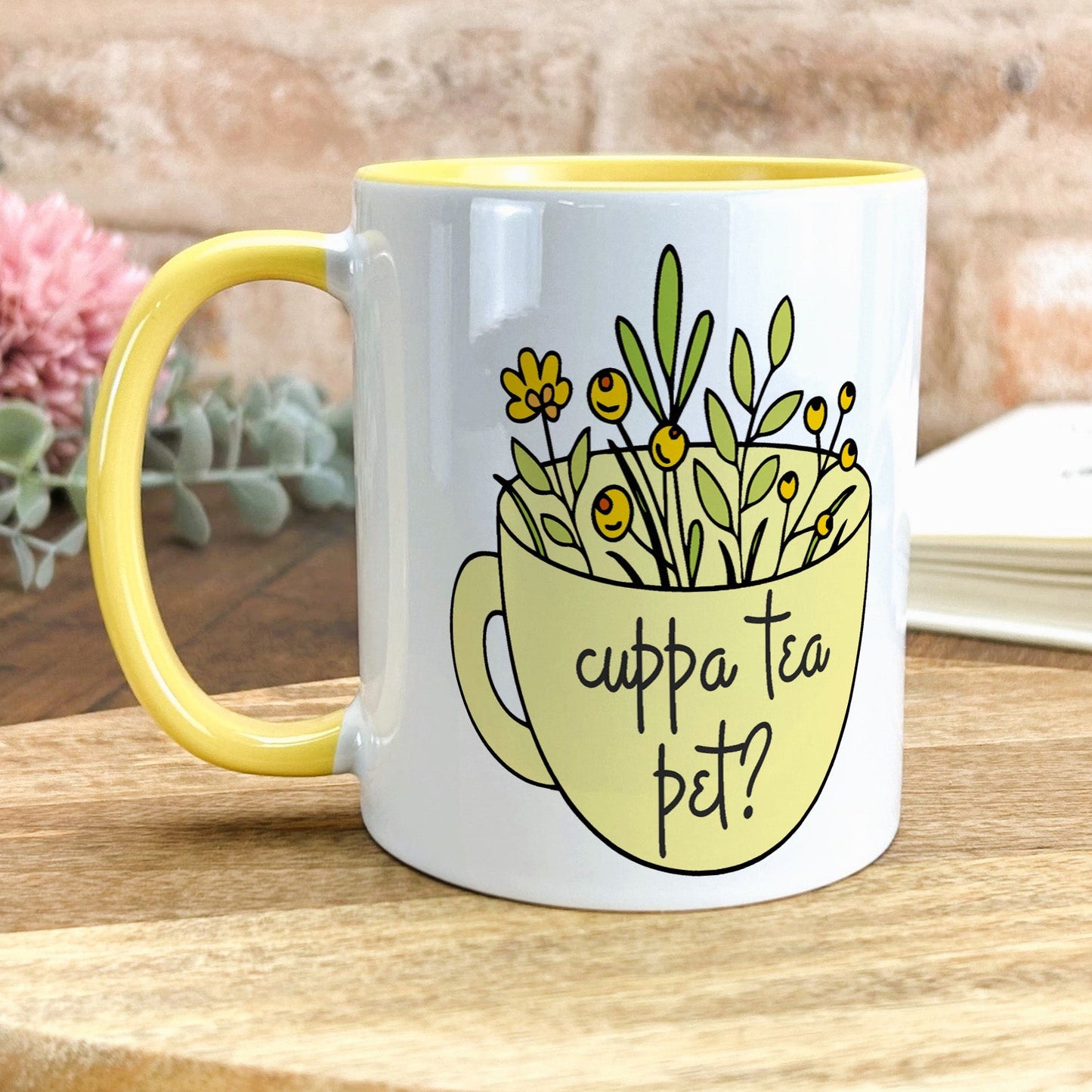 a yellow and white coffee mug with flowers in it