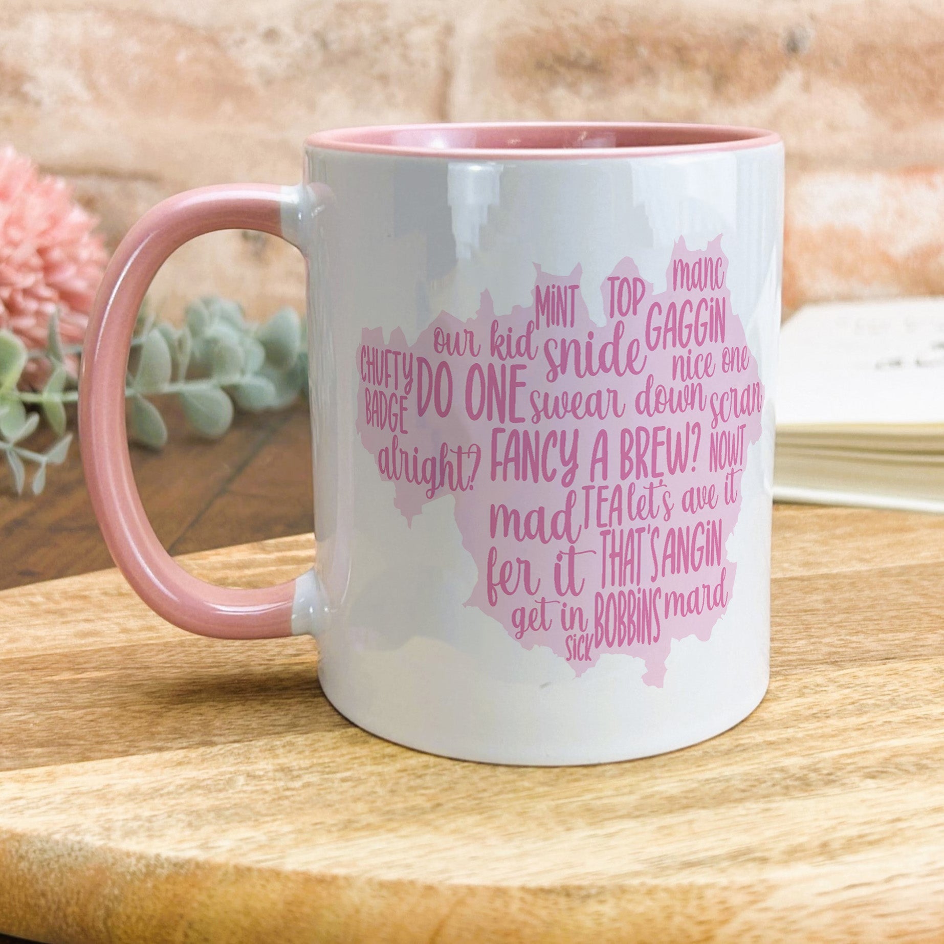 a pink and white coffee mug sitting on top of a wooden table