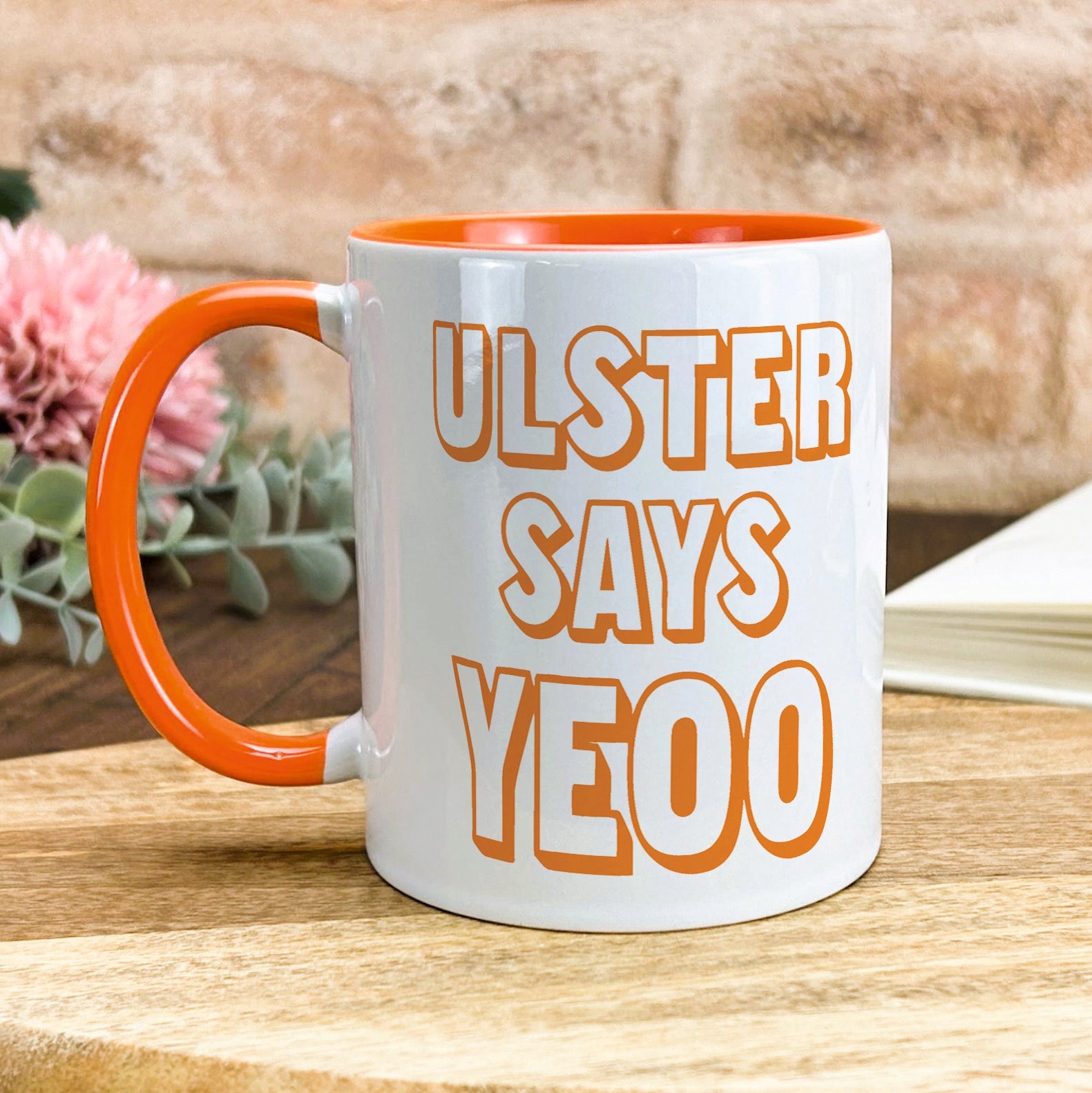 a white and orange coffee mug sitting on top of a wooden table
