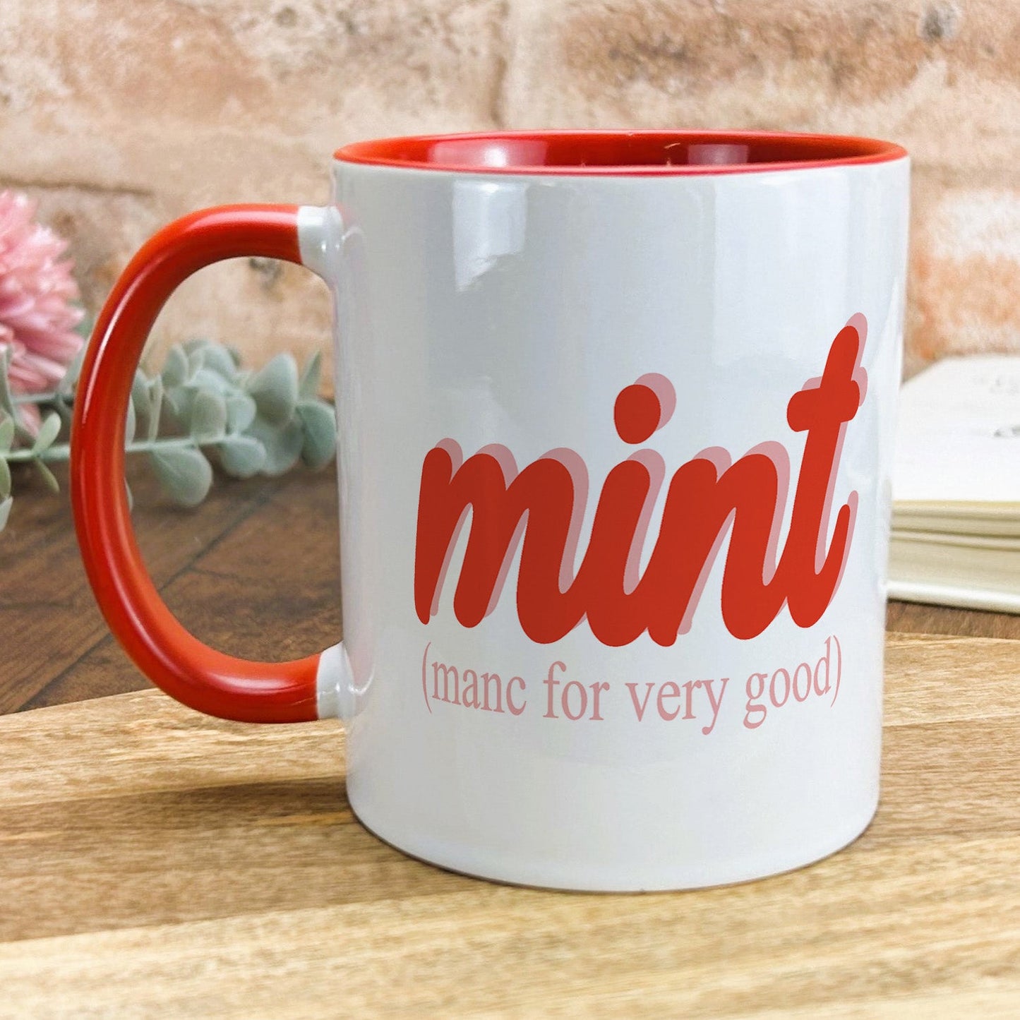 a red and white coffee mug sitting on top of a wooden table