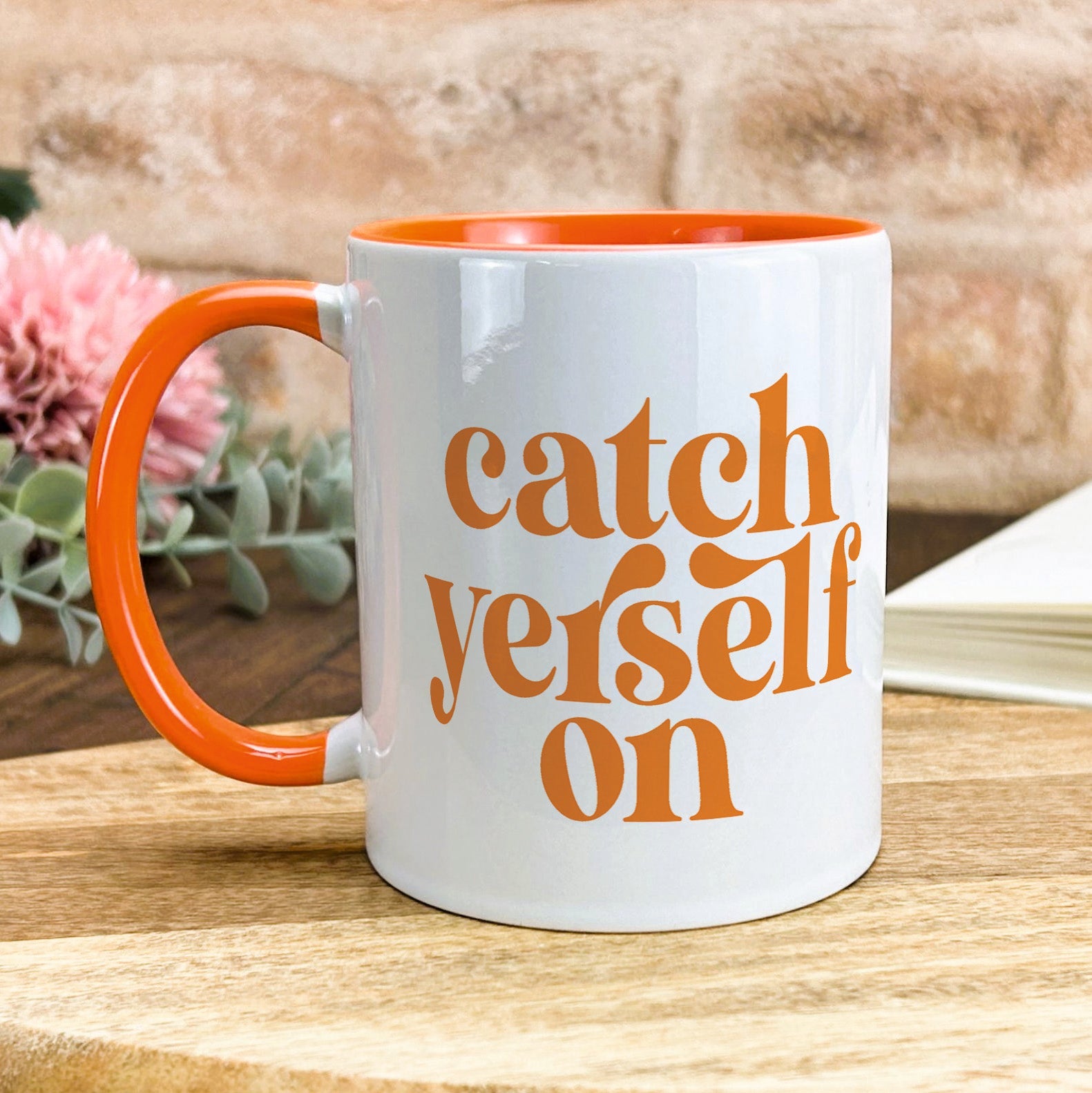 a white and orange coffee mug sitting on top of a wooden table