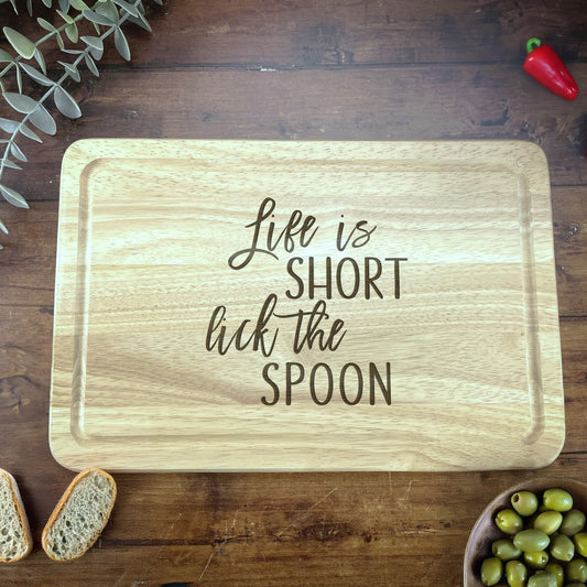 a wooden cutting board that says life is short but the spoon