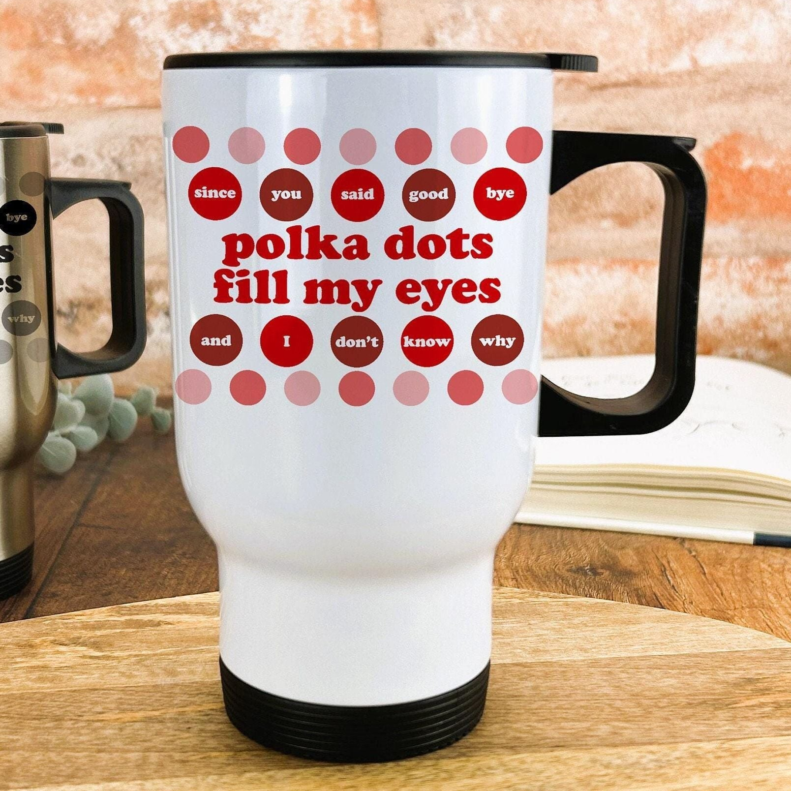 A white travel mug with a black handle, featuring a humorous text design that reads "polka dots fill my eyes and I don't know why".
