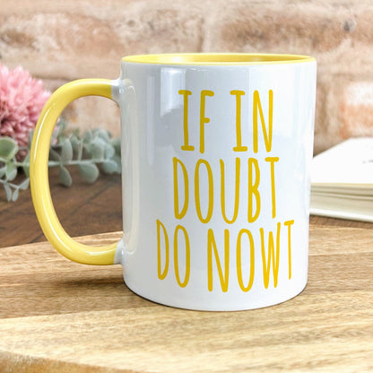 a yellow and white coffee mug sitting on top of a wooden table