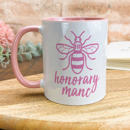 a pink and white coffee mug with a bee on it