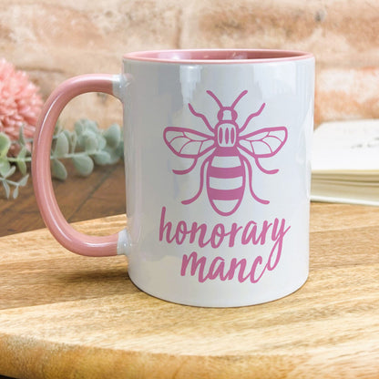 a pink and white coffee mug with a bee on it