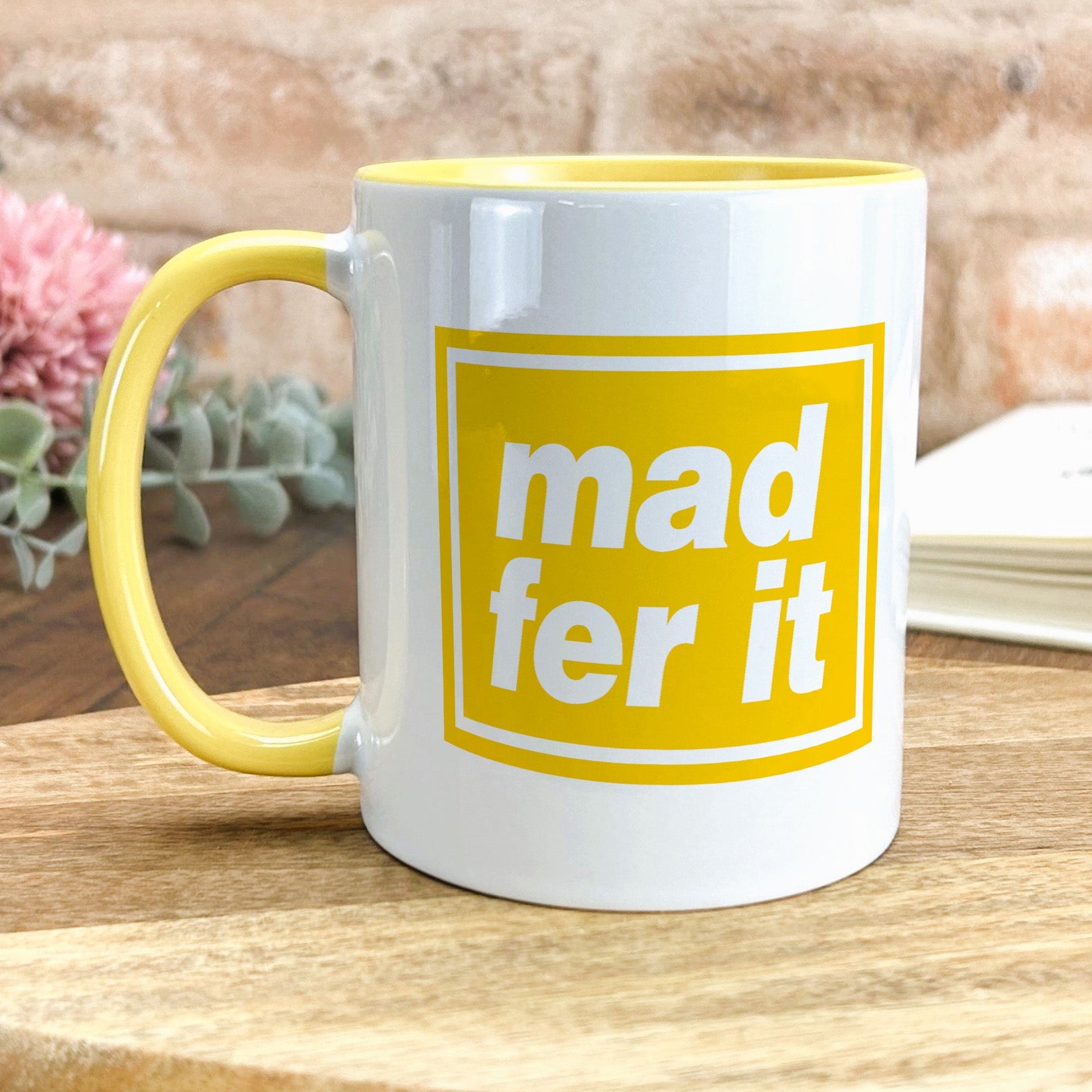 a yellow and white mug sitting on top of a wooden table