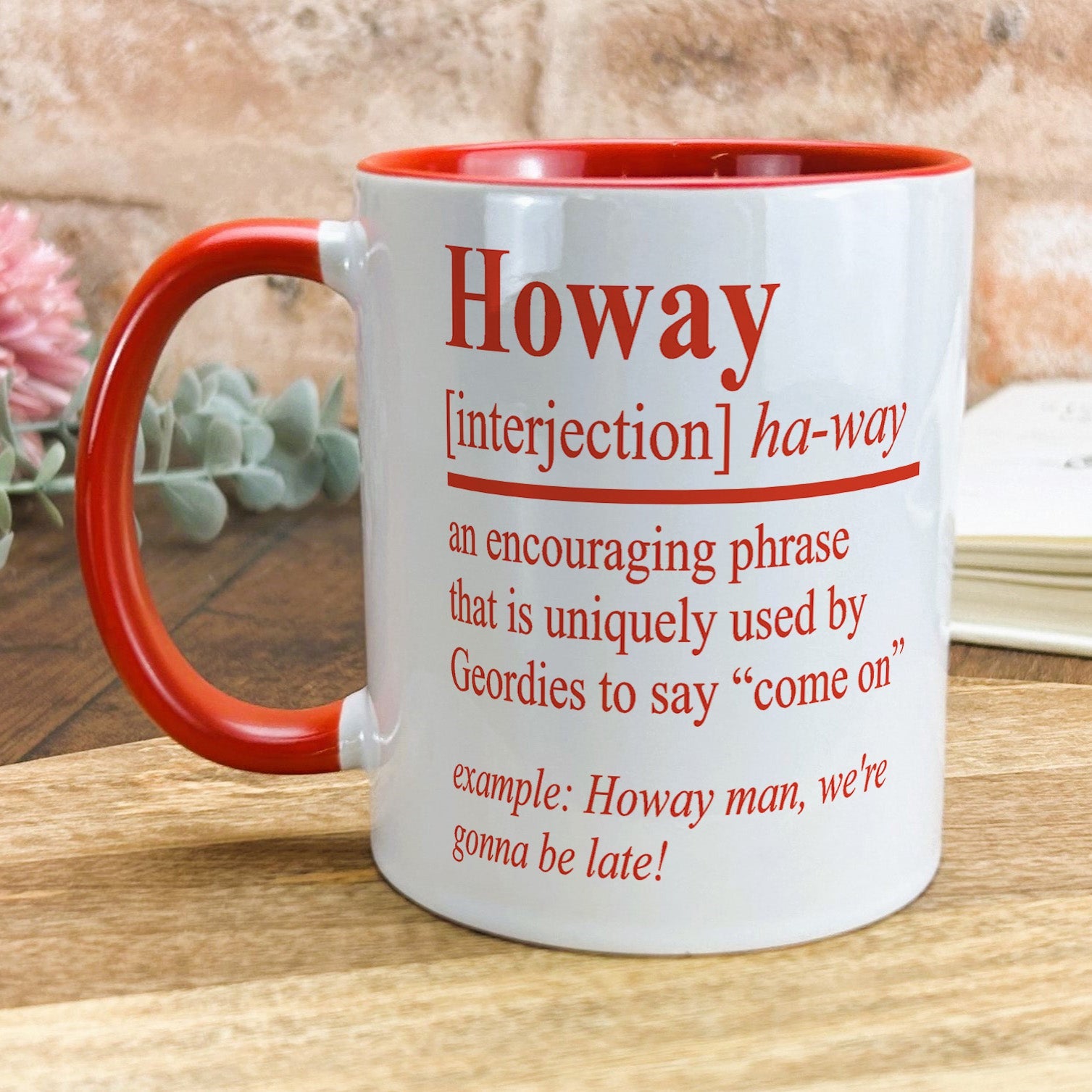 a red and white coffee mug sitting on top of a wooden table