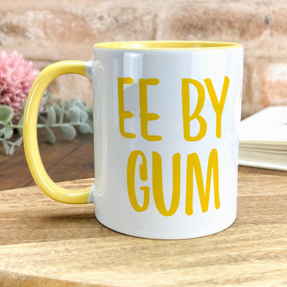 a yellow and white coffee mug sitting on top of a wooden table