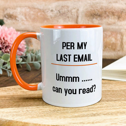 a white and orange coffee mug sitting on top of a wooden table