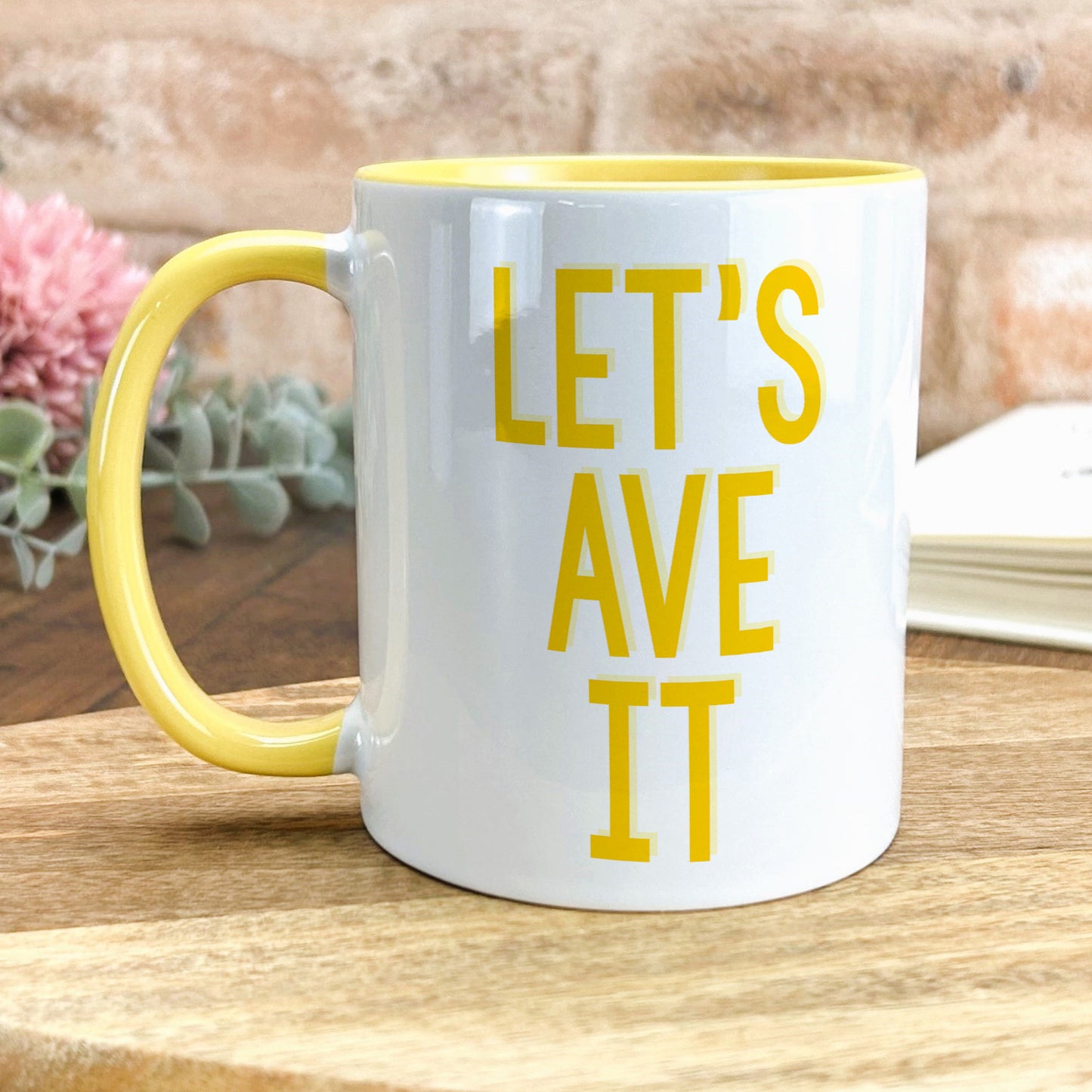a yellow and white coffee mug sitting on top of a wooden table
