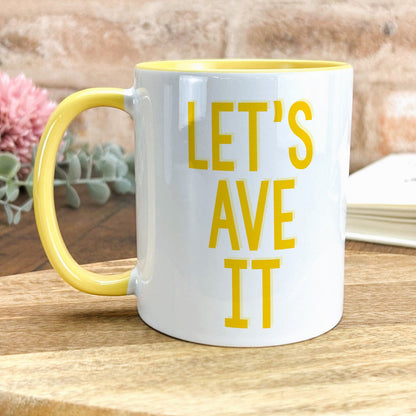 a yellow and white coffee mug sitting on top of a wooden table