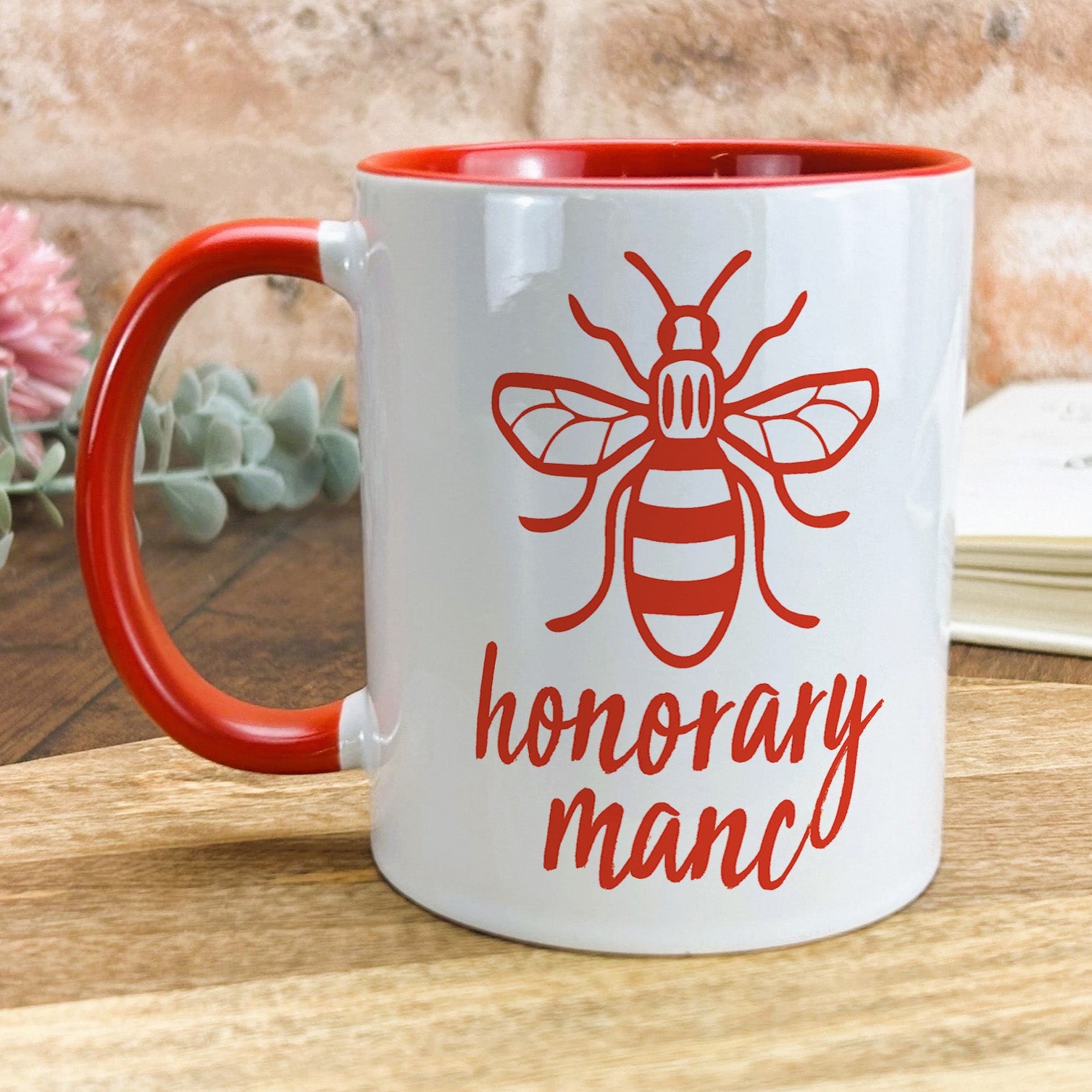a red and white coffee mug with a bee on it