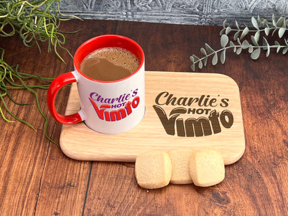 A red and white mug with the text "Charlie's Hot Vimio" sits on a wooden tray, accompanied by a few cookies and a plant.