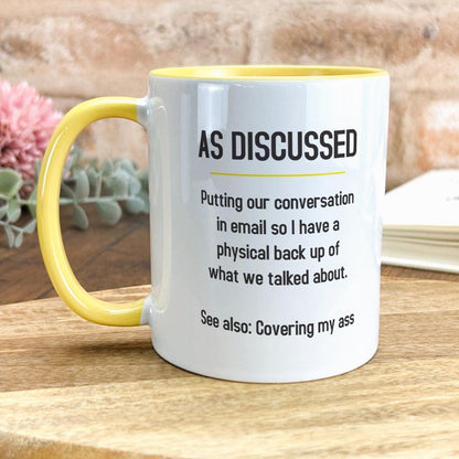 a yellow and white coffee mug sitting on top of a wooden table