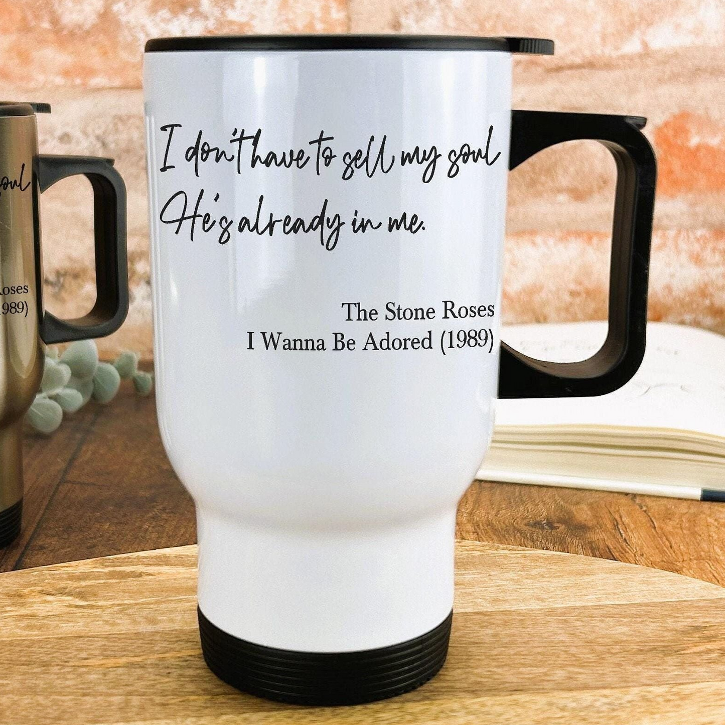 A white travel mug with black text and a quote from the song "The Stone Roses" by The Rockettes.