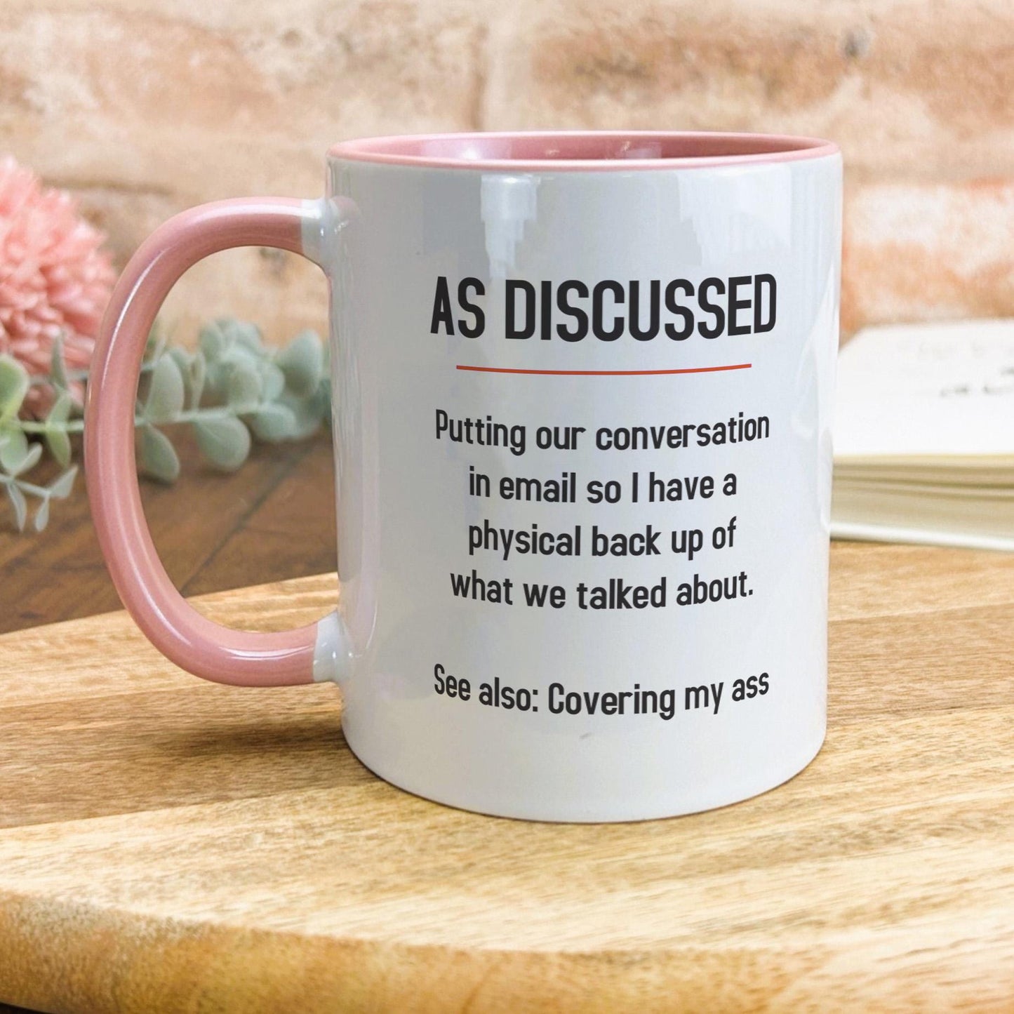 a pink and white coffee mug sitting on top of a wooden table