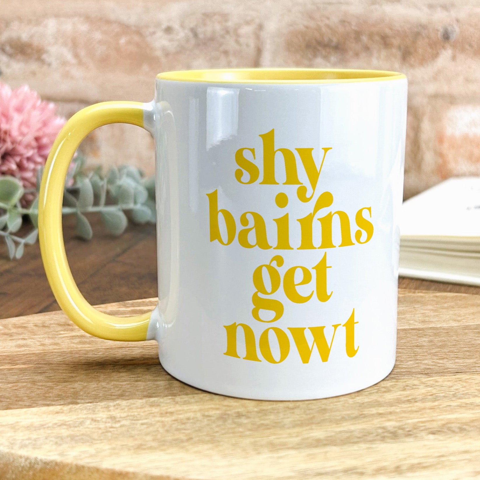 a yellow and white coffee mug sitting on top of a wooden table