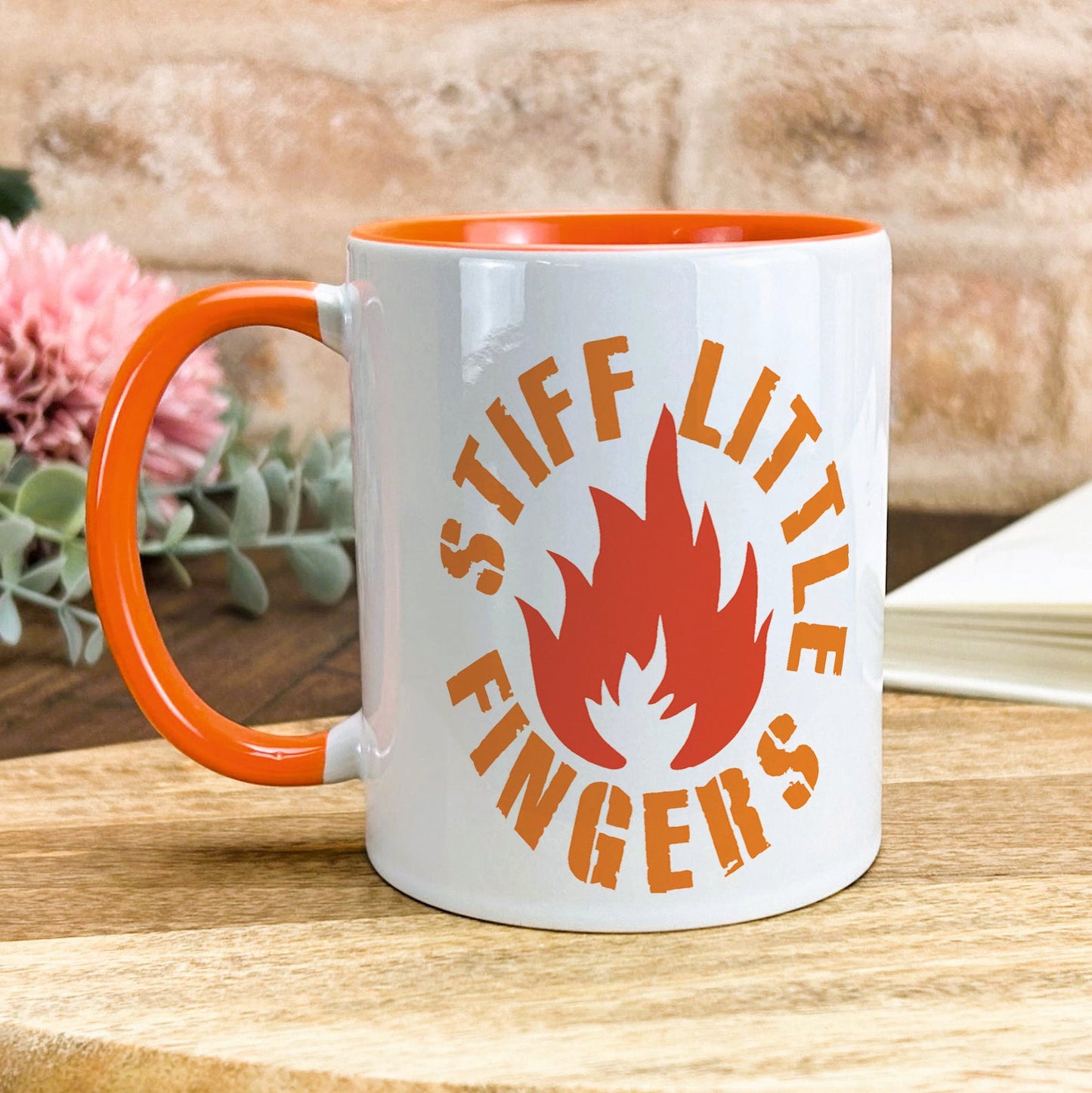 a white and orange coffee mug sitting on top of a wooden table
