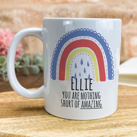 A white ceramic mug with a colorful rainbow design and text that reads "Ellie, you are nothing short of amazing".