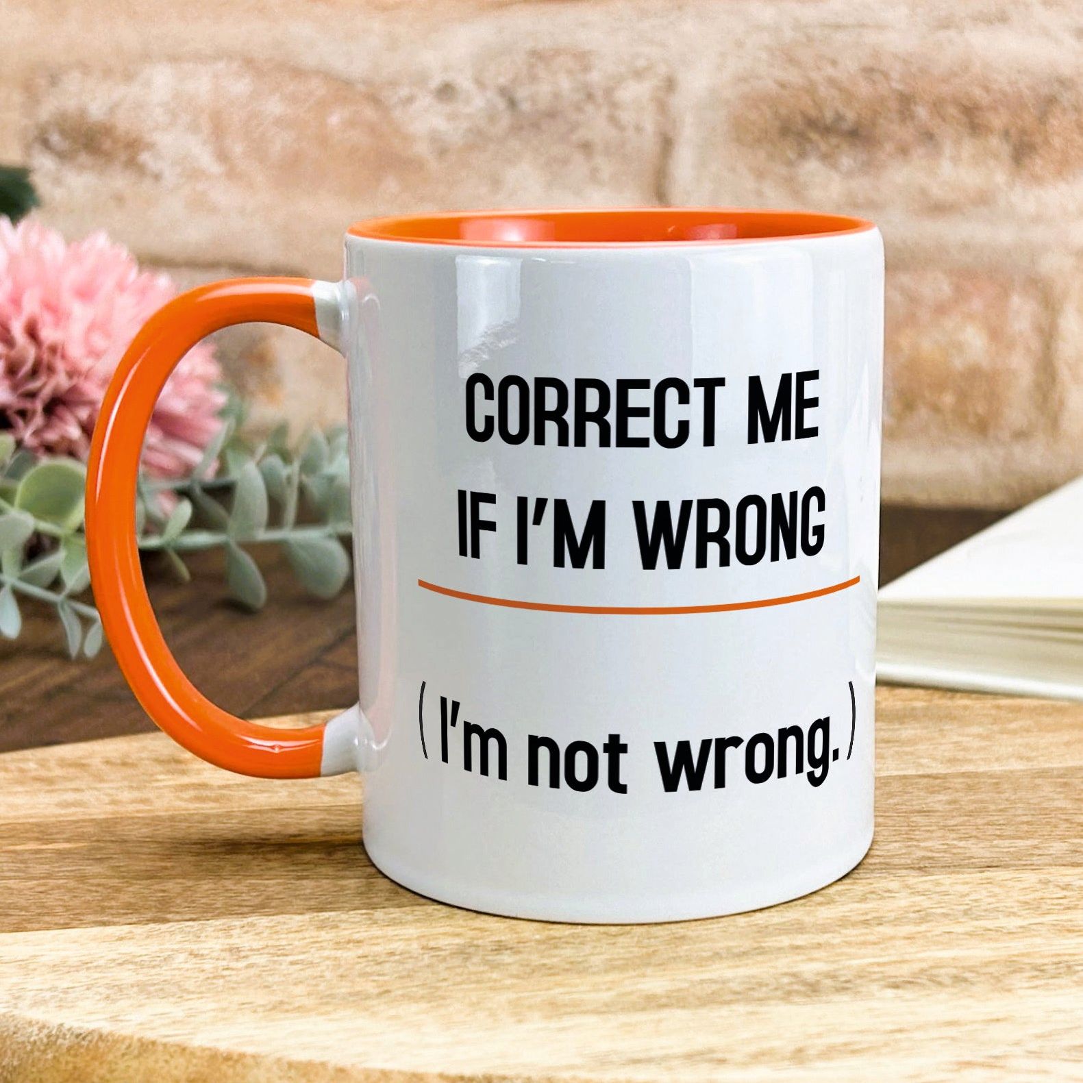 a white and orange coffee mug sitting on top of a wooden table