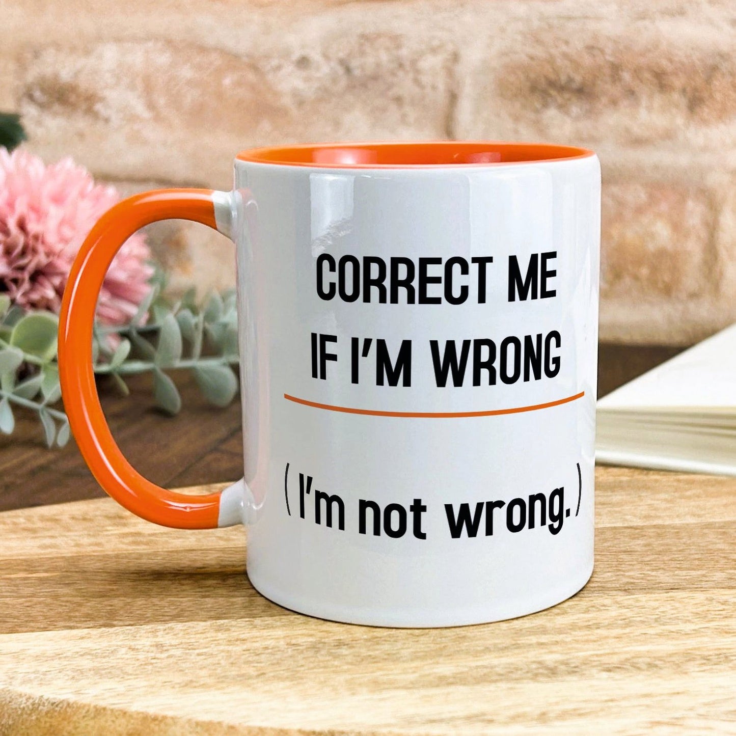 a white and orange coffee mug sitting on top of a wooden table