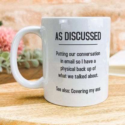 a white coffee mug sitting on top of a wooden table